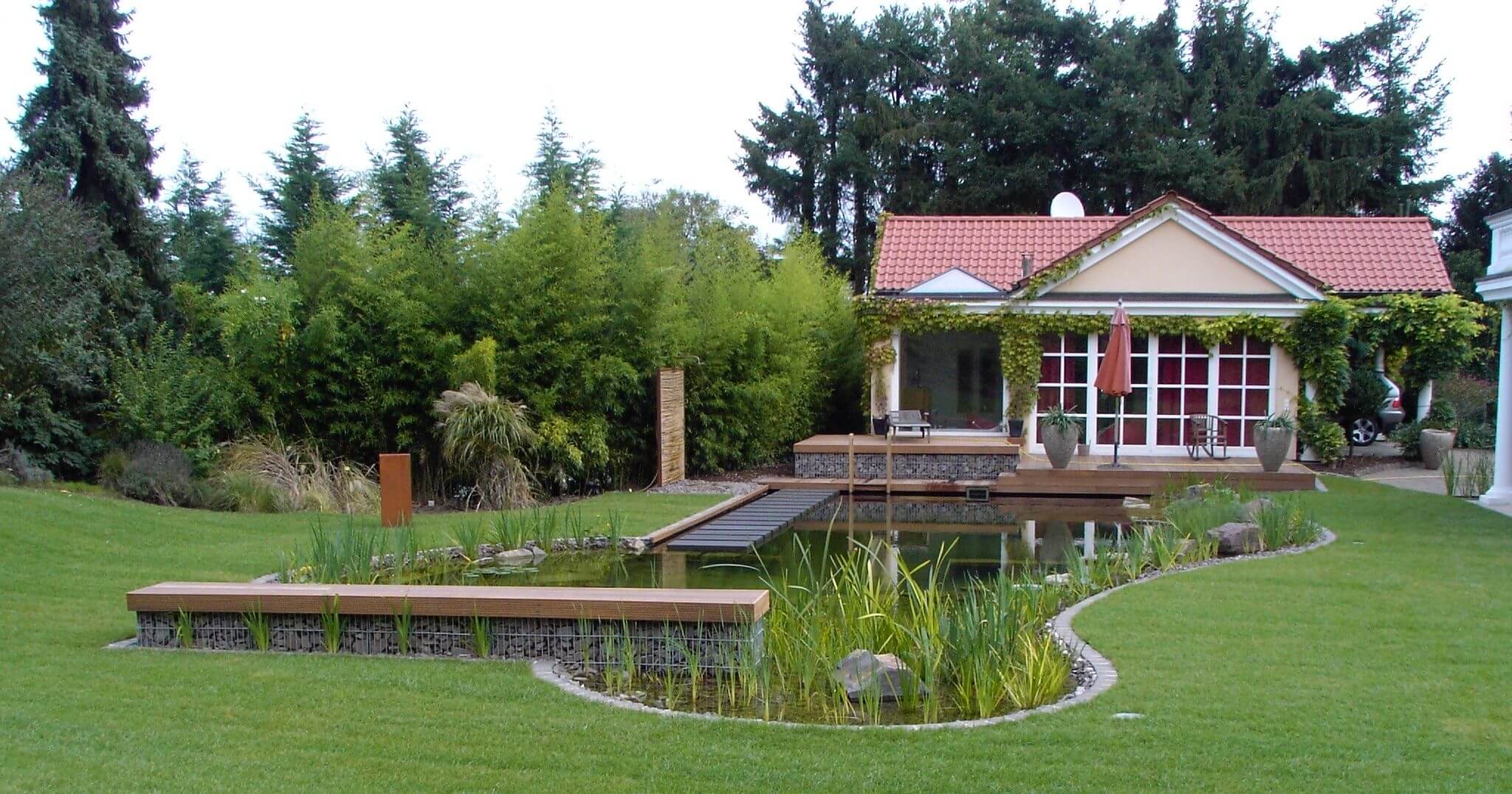 Ruhige Wasserfläche eines Schwimmteichs mit Uferbepflanzung